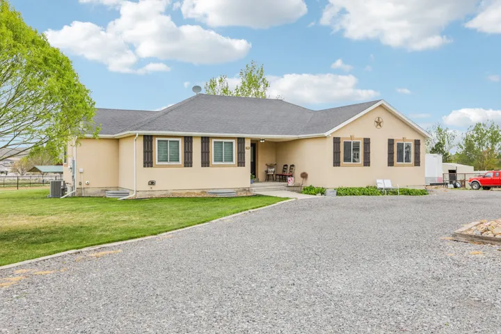 Ranch-style home with a shingled roof, stucco siding, and covered porch