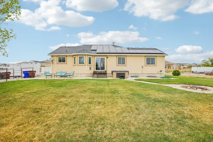 Back of house with a patio, entry steps, solar panels, and stucco siding