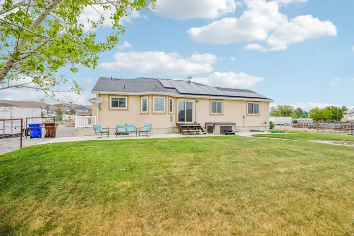 Back of property featuring a patio, roof mounted solar panels, stucco siding, and entry steps