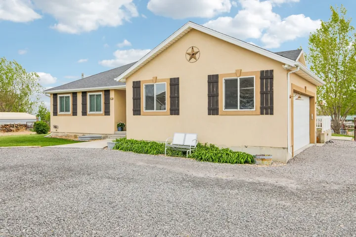 View of front of property with stucco siding, driveway, an attached garage, and roof with shingles