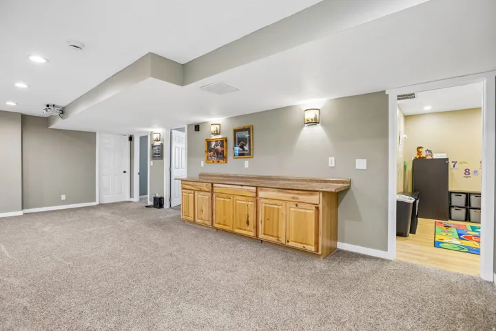 Bar with light carpet, recessed lighting, light countertops, and light wood finish cabinetry