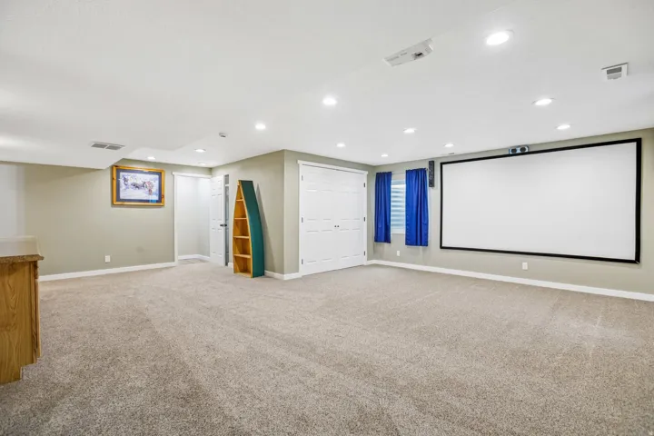 Cinema room with light colored carpet and recessed lighting