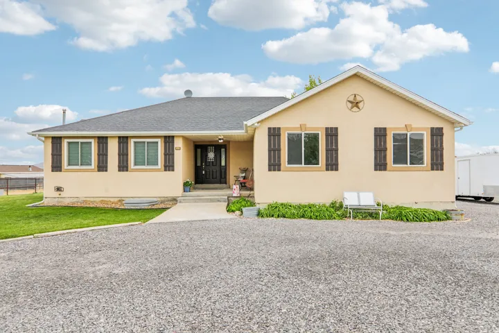 View of front of property with stucco, a shingled roof, and a front yard