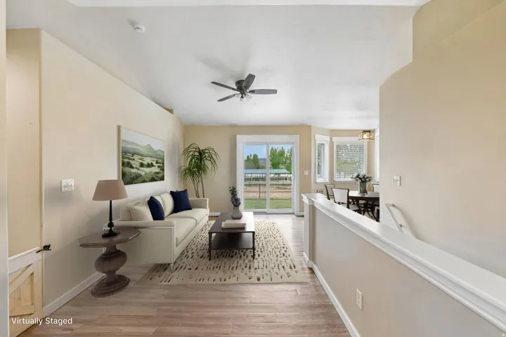 Vaulted ceiling with ceiling fan, wood-finish flooring, sliding glass door, multiple windows with blinds, and recessed lighting
