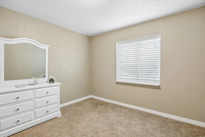 Unfurnished bedroom with light colored carpet and a textured wall