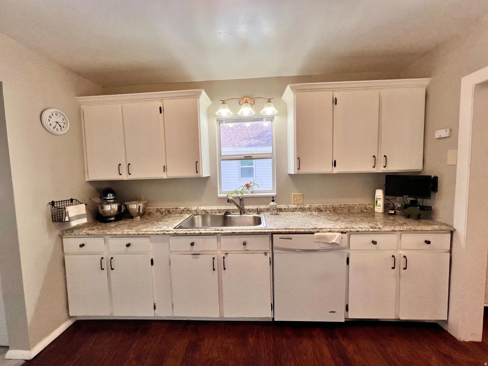 Kitchen featuring light countertops, dishwasher, dark wood finished floors, and white cabinetry