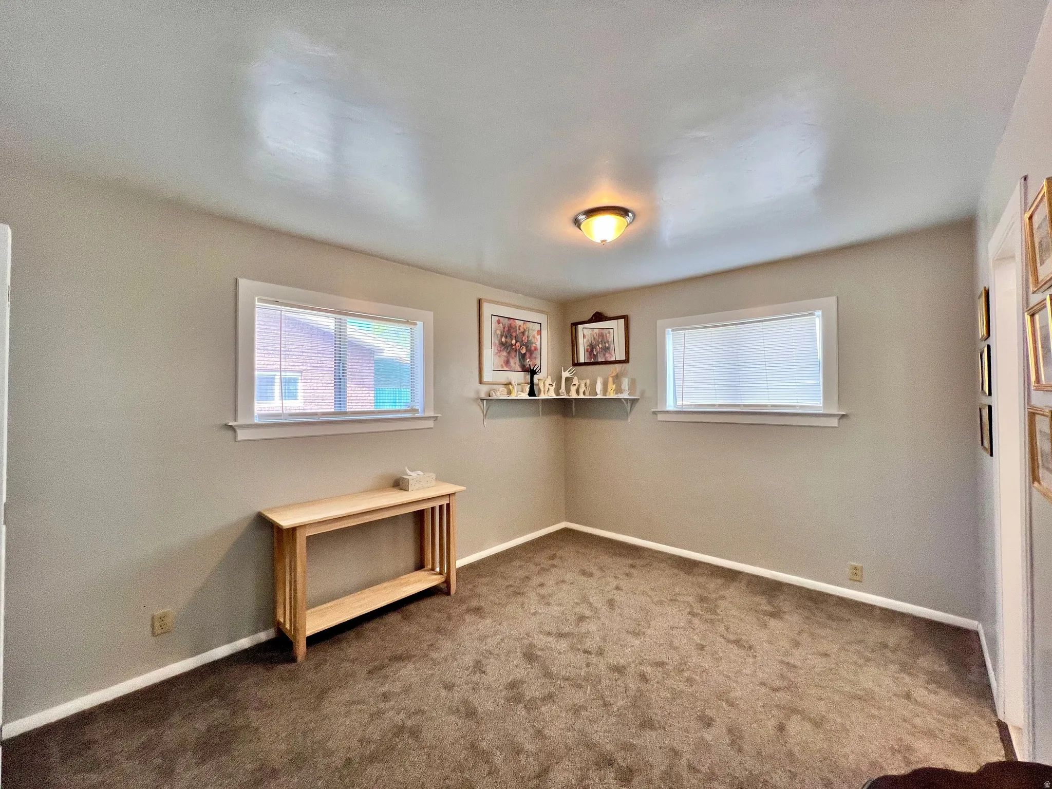 Unfurnished room featuring dark colored carpet and healthy amount of natural light