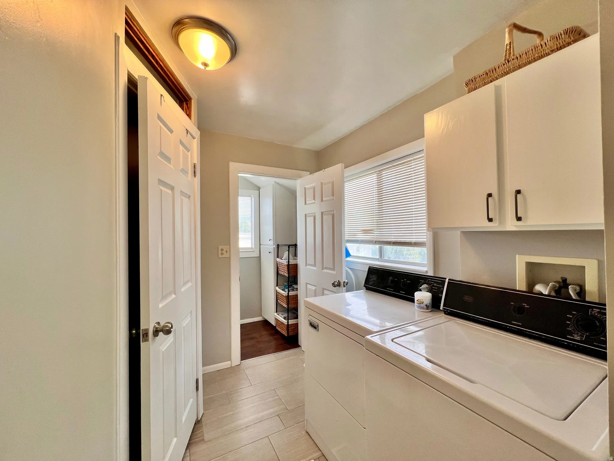 Laundry area featuring cabinet space, washer and clothes dryer, and light wood-type flooring