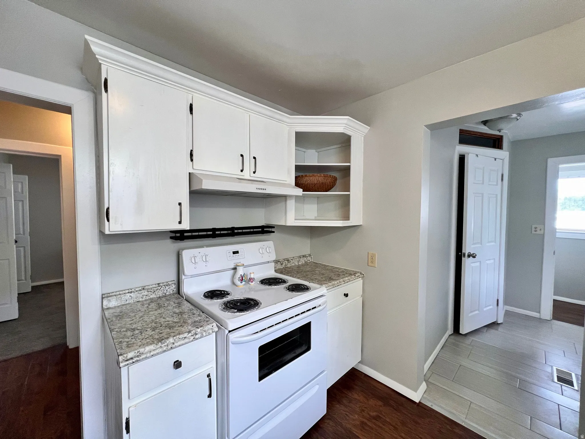 Kitchen with white electric range, light countertops, dark wood-style flooring, and white cabinetry