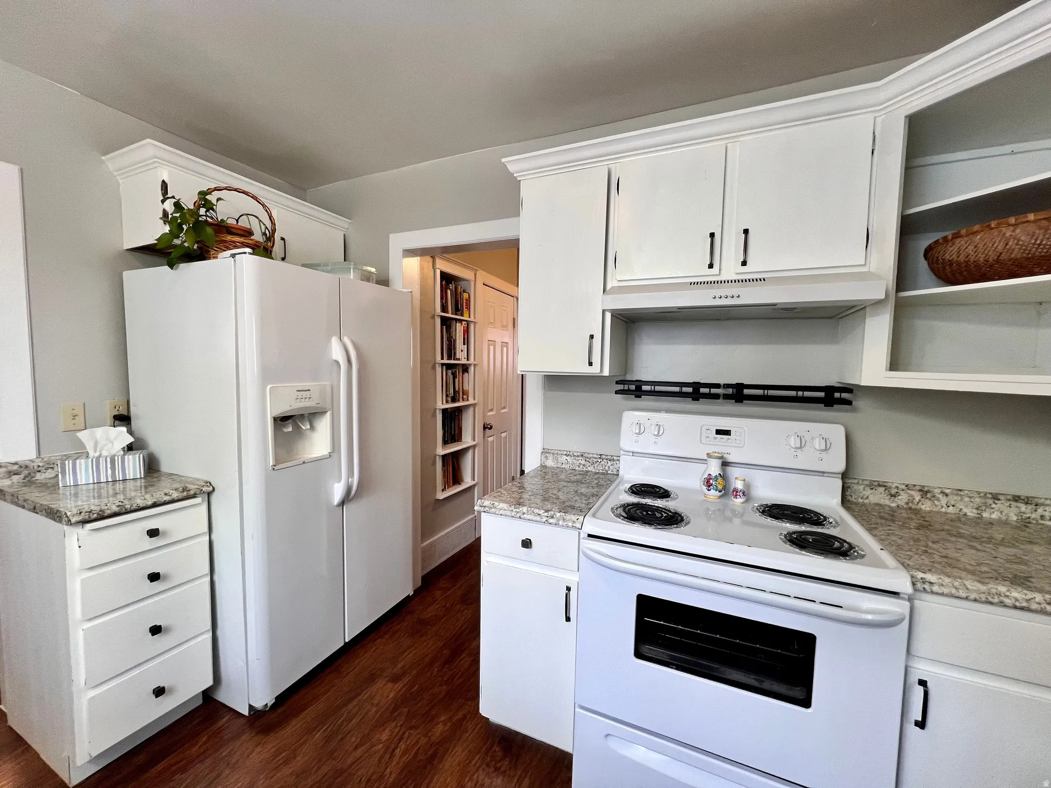 Kitchen with white appliances, white cabinets, and dark wood finished floors