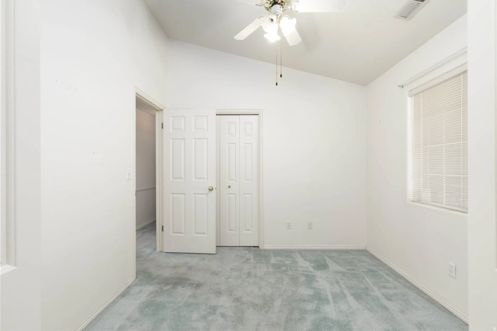 Unfurnished bedroom with lofted ceiling, light colored carpet, a ceiling fan, and a closet