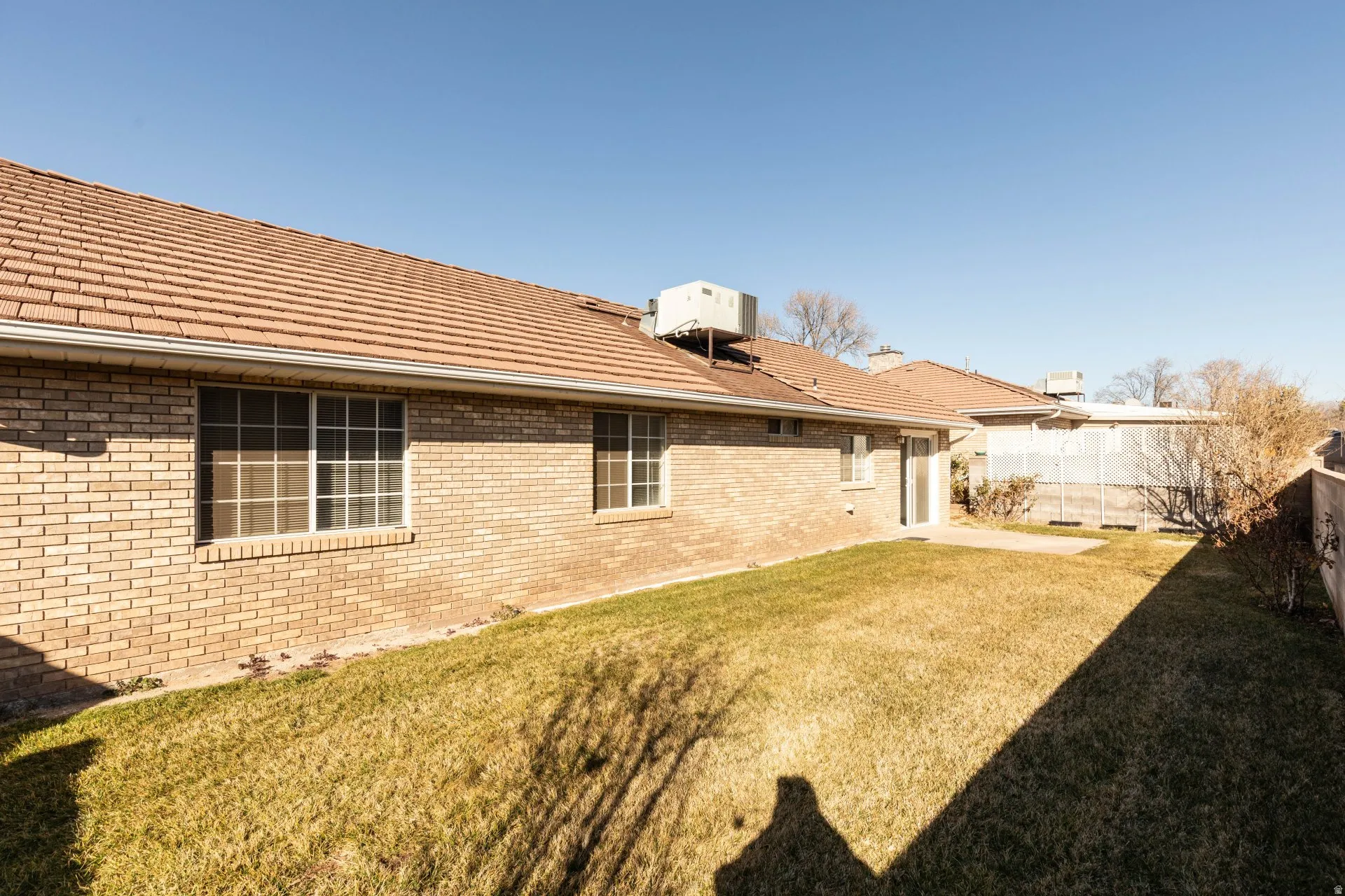 Back of house with brick siding, a tile roof, and a patio