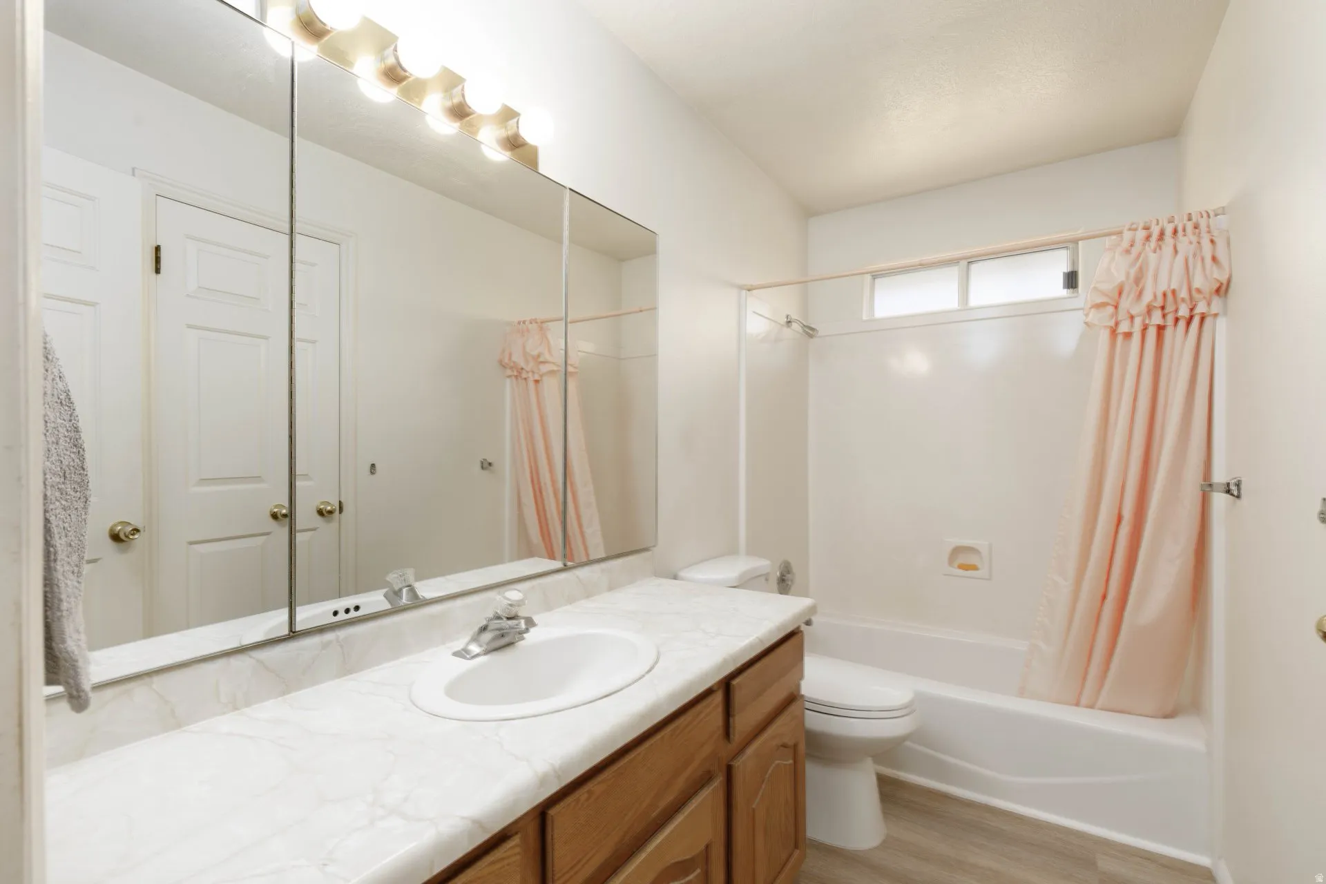 Bathroom featuring vanity, shower / bath combo, and light wood-style flooring