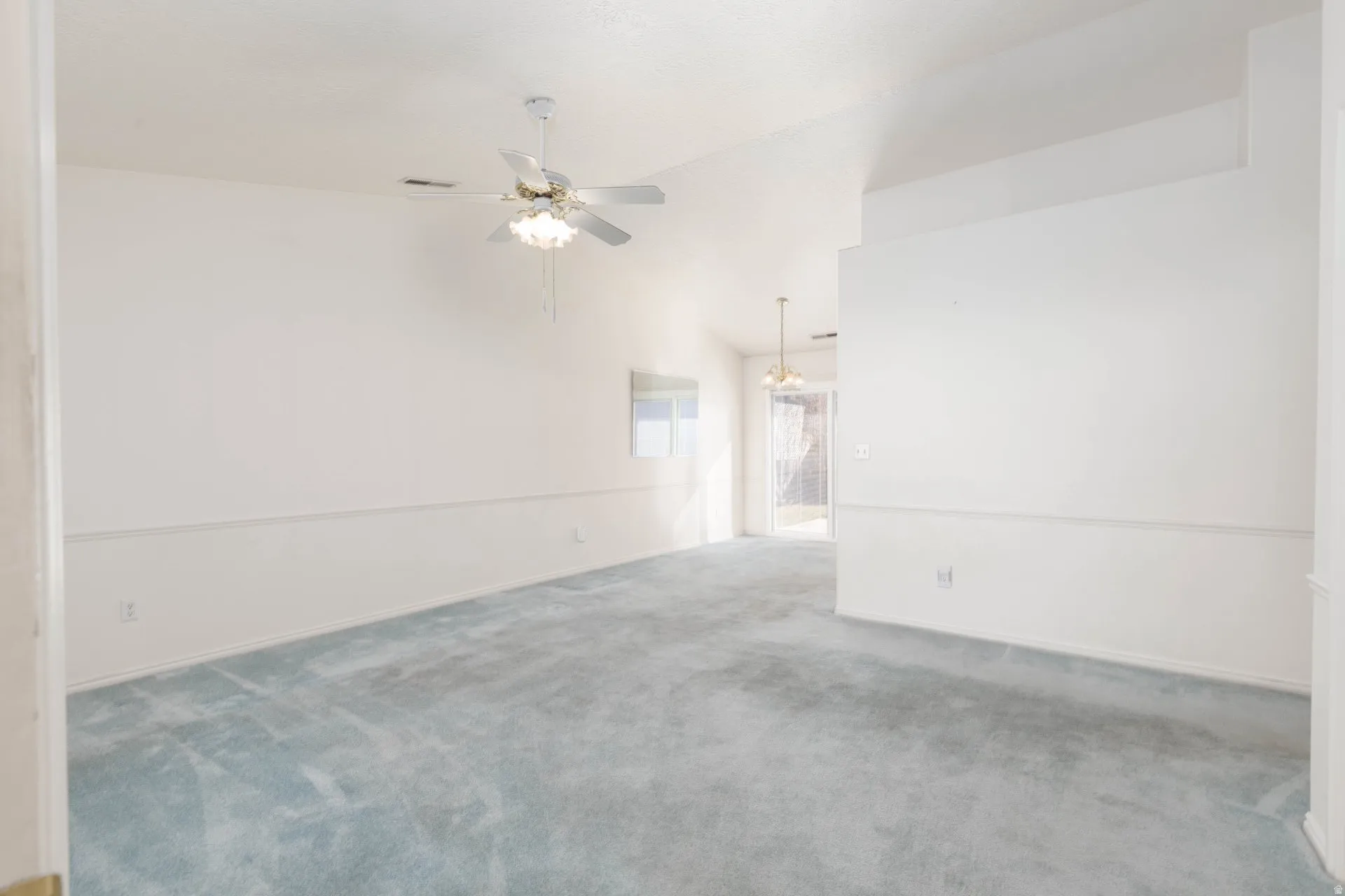 Carpeted spare room with a ceiling fan and vaulted ceiling