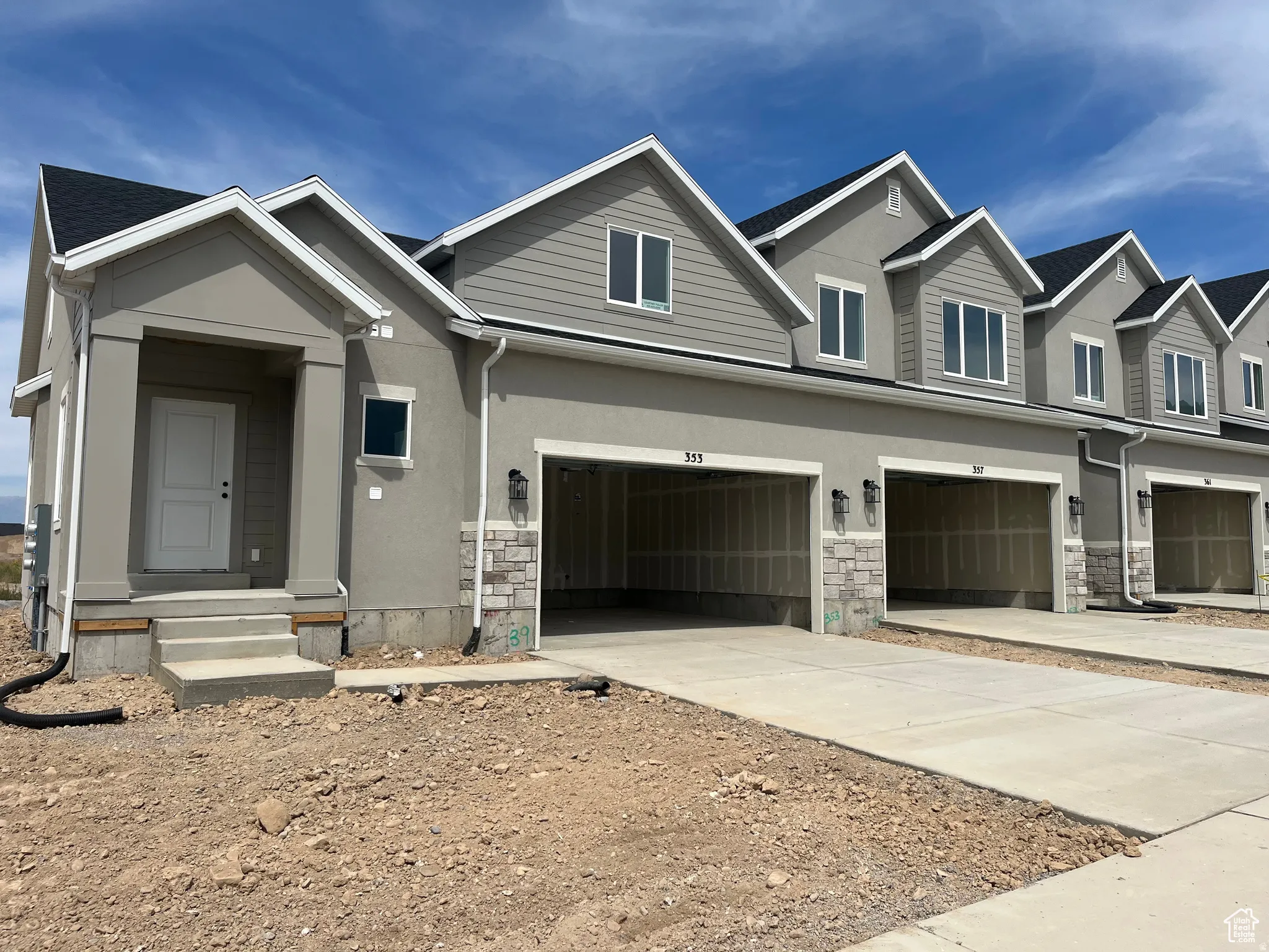 View of front of house with driveway, stone siding, a garage, and stucco siding