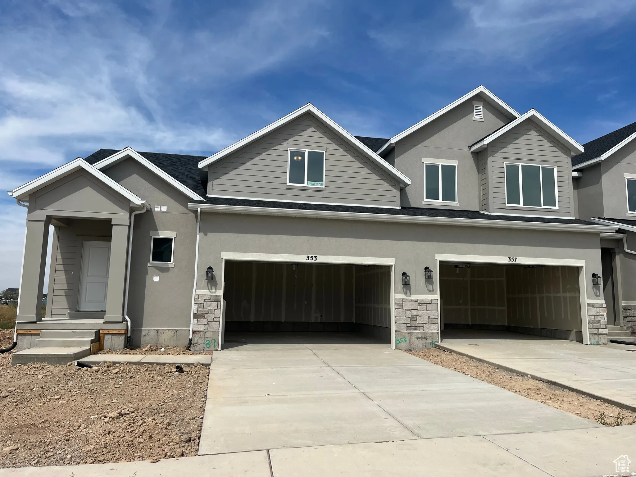 View of front of property with stone siding, stucco siding, driveway, and a garage