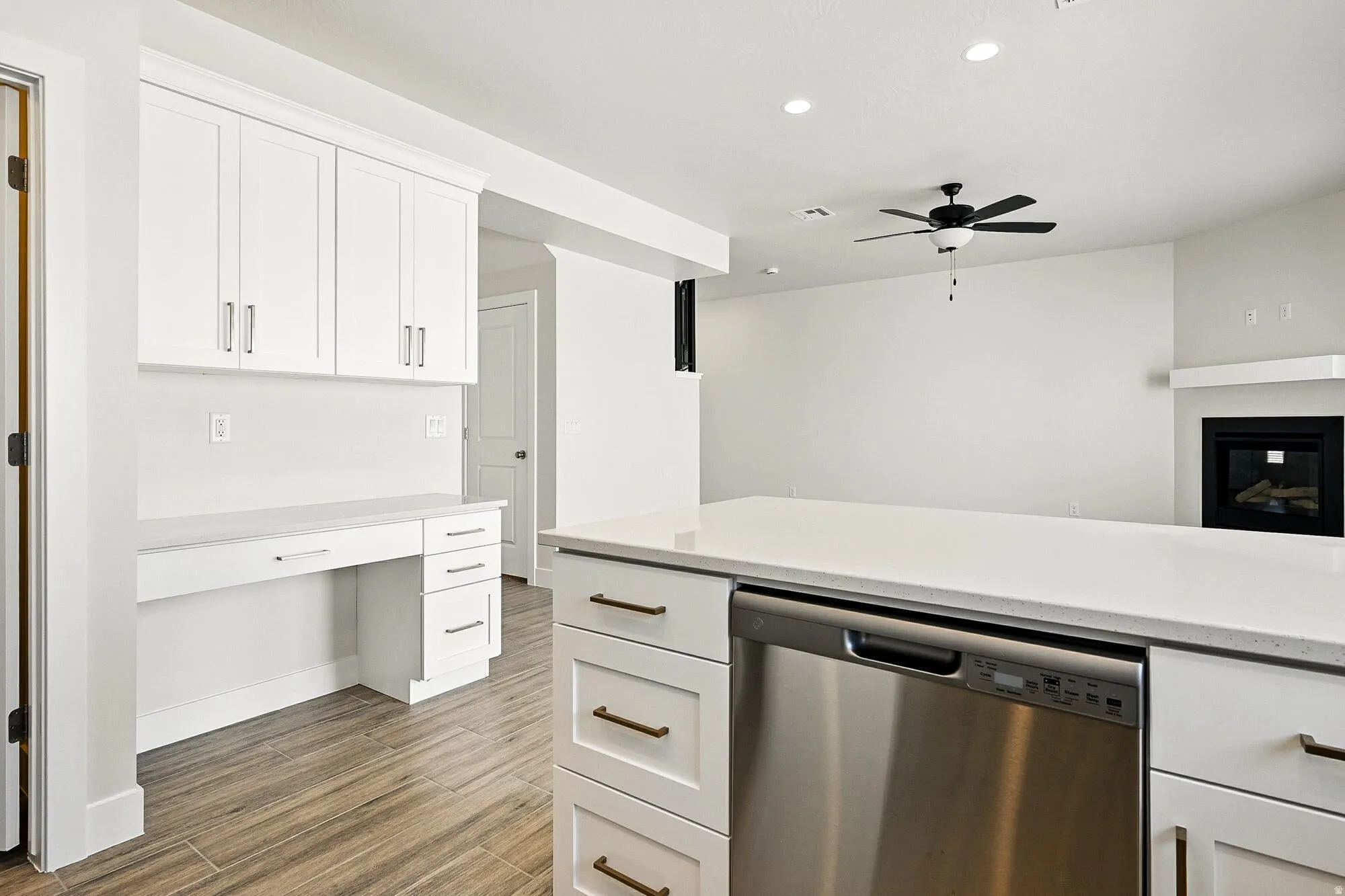 Kitchen with white cabinets, dishwasher, dark wood-style floors, light stone countertops, and ceiling fan