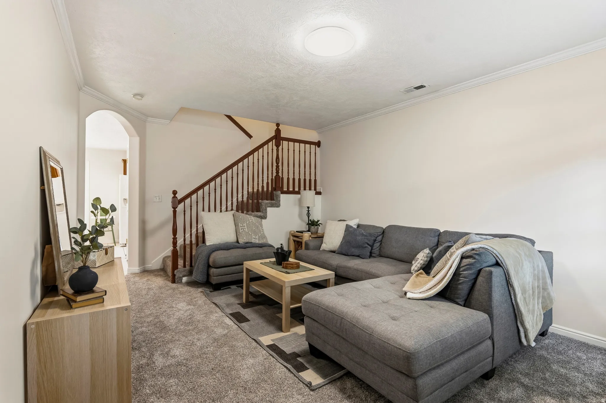 Carpeted living area featuring arched walkways and crown molding
