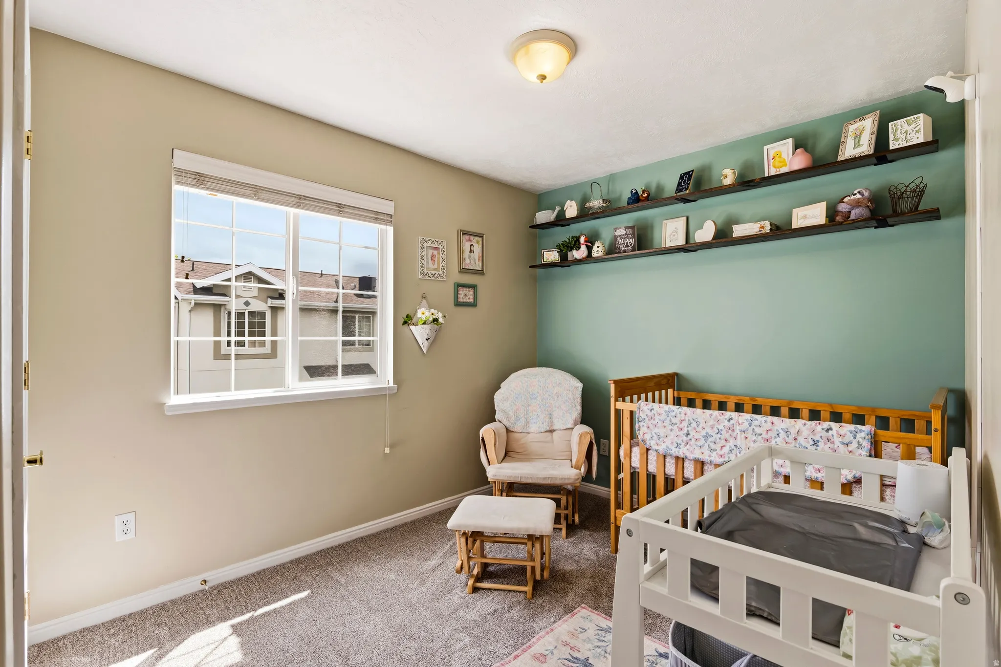 Carpeted bedroom featuring a crib and baseboards
