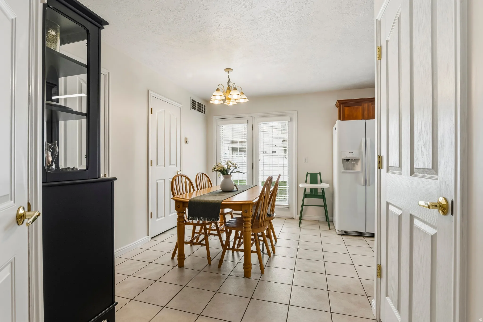 Dining area featuring light tile patterned flooring, suspended lighting, and a textured ceiling