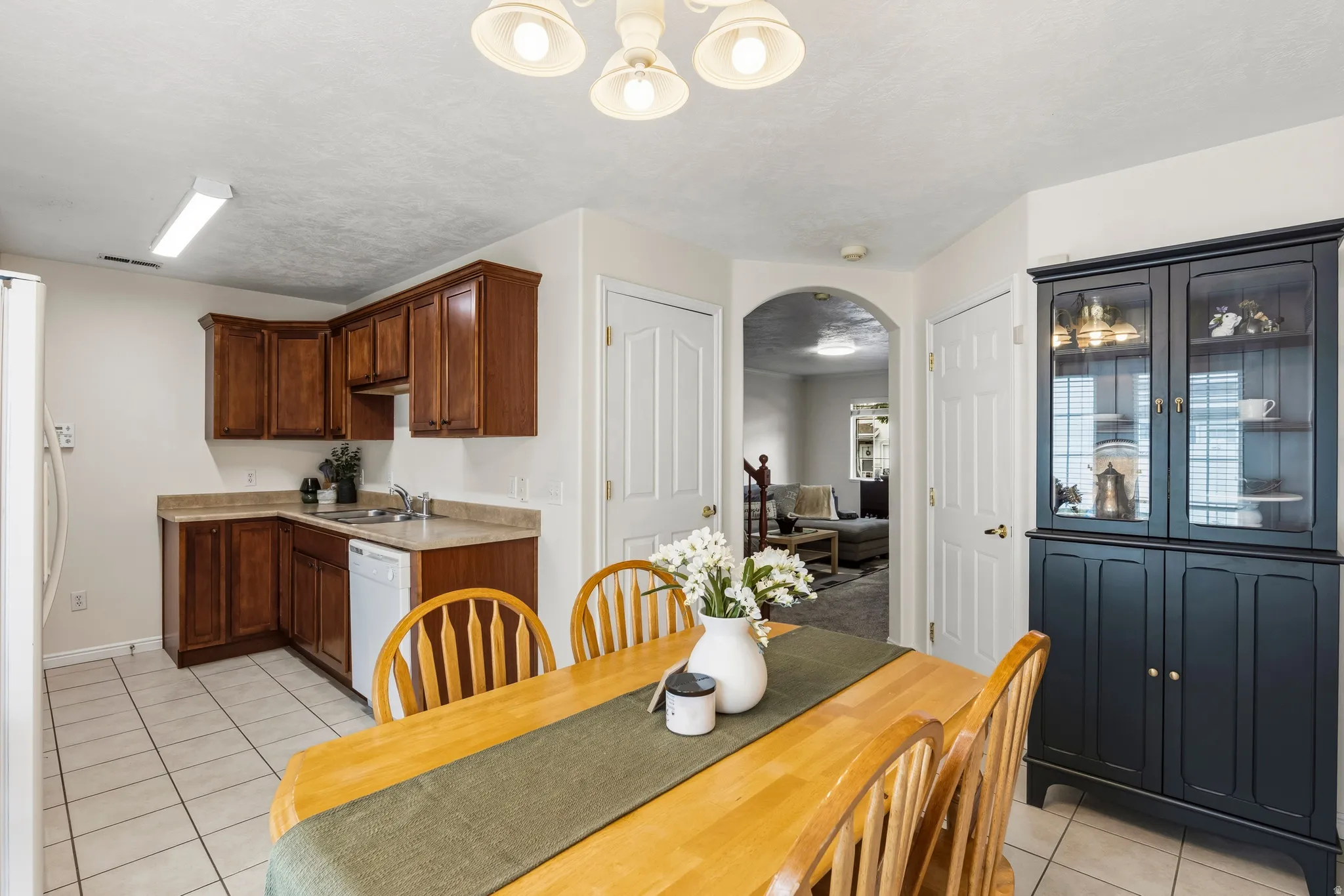 Dining area with light tile patterned flooring, arched walkways, and a textured ceiling