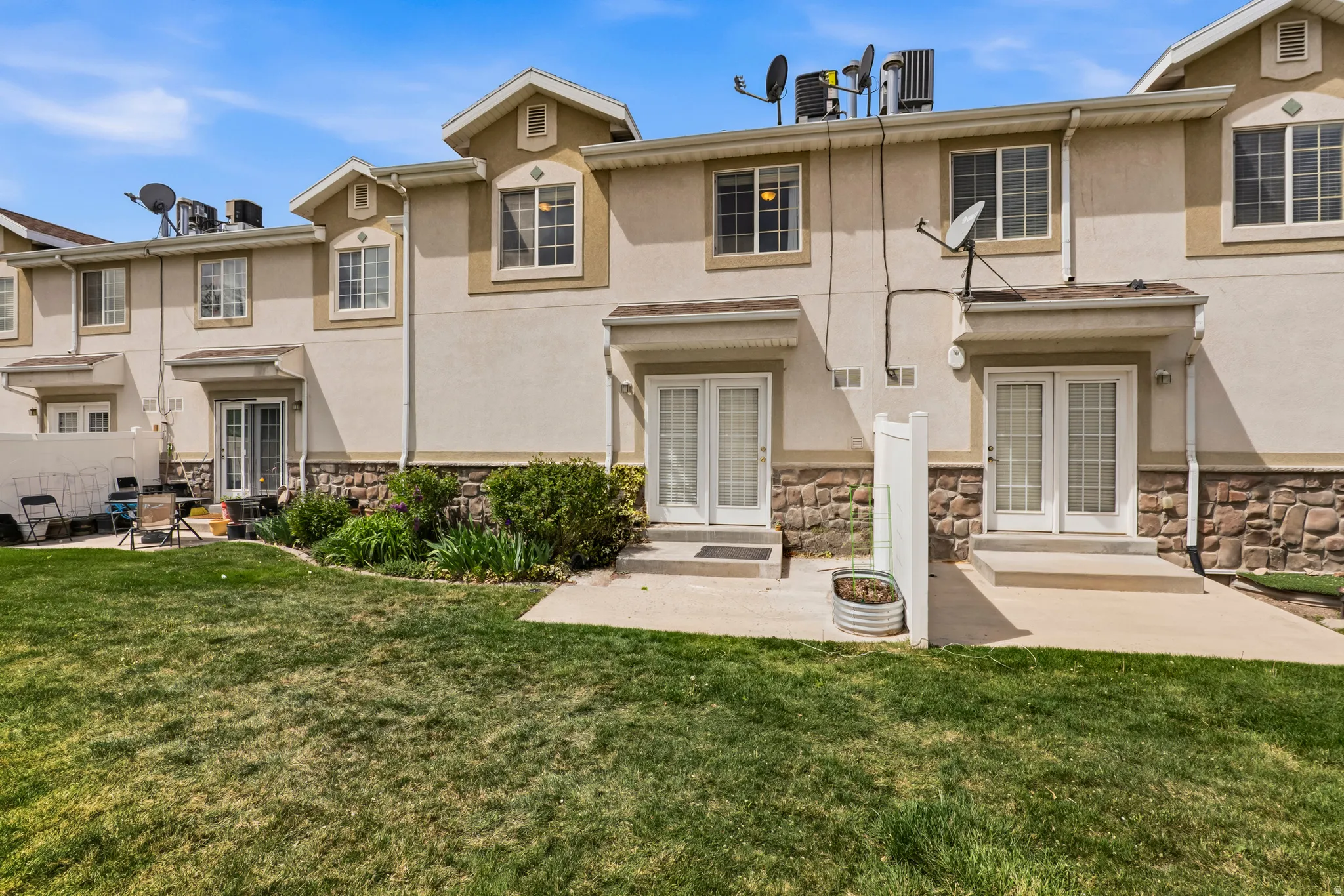 Rear view of house featuring french doors, stone siding, and stucco siding