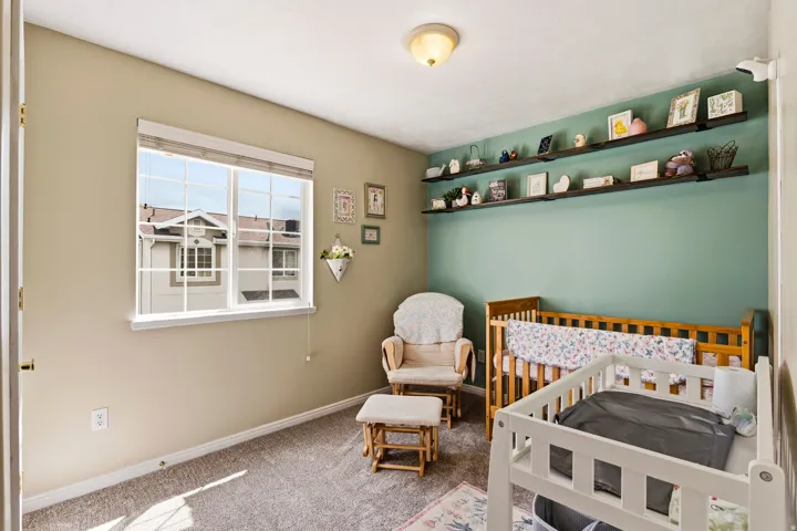 Carpeted bedroom featuring a crib and baseboards