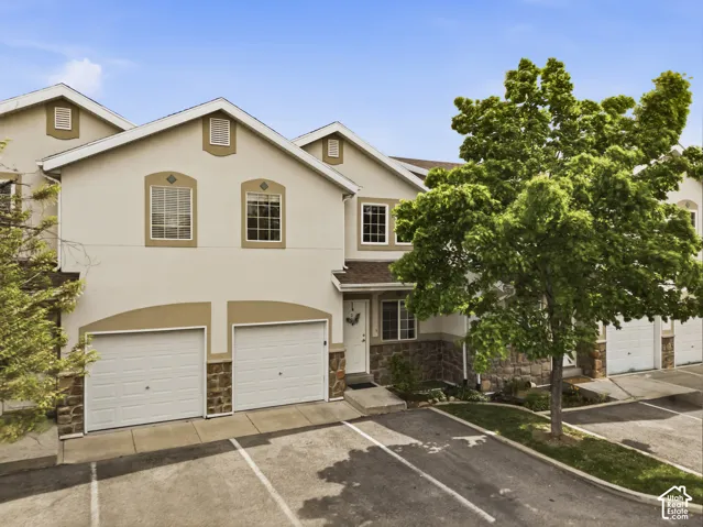 Traditional-style home featuring stone siding, stucco siding, and a garage
