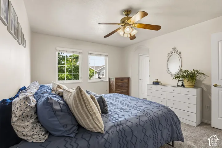 Bedroom with carpet flooring, ceiling fan, and arched walkways