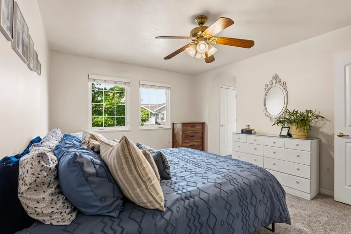 Bedroom with carpet flooring, ceiling fan, and arched walkways