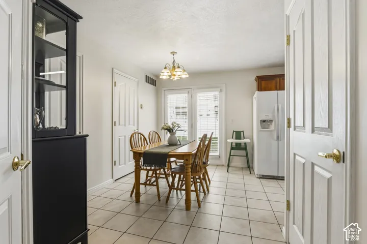 Dining area featuring light tile patterned flooring, suspended lighting, and a textured ceiling