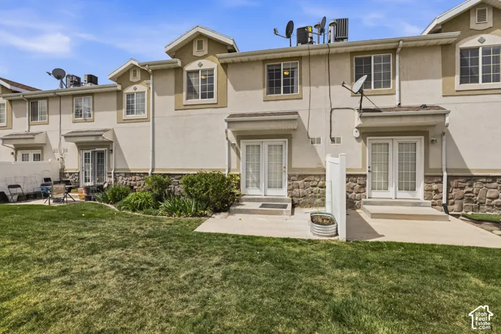 Rear view of house featuring french doors, stone siding, and stucco siding