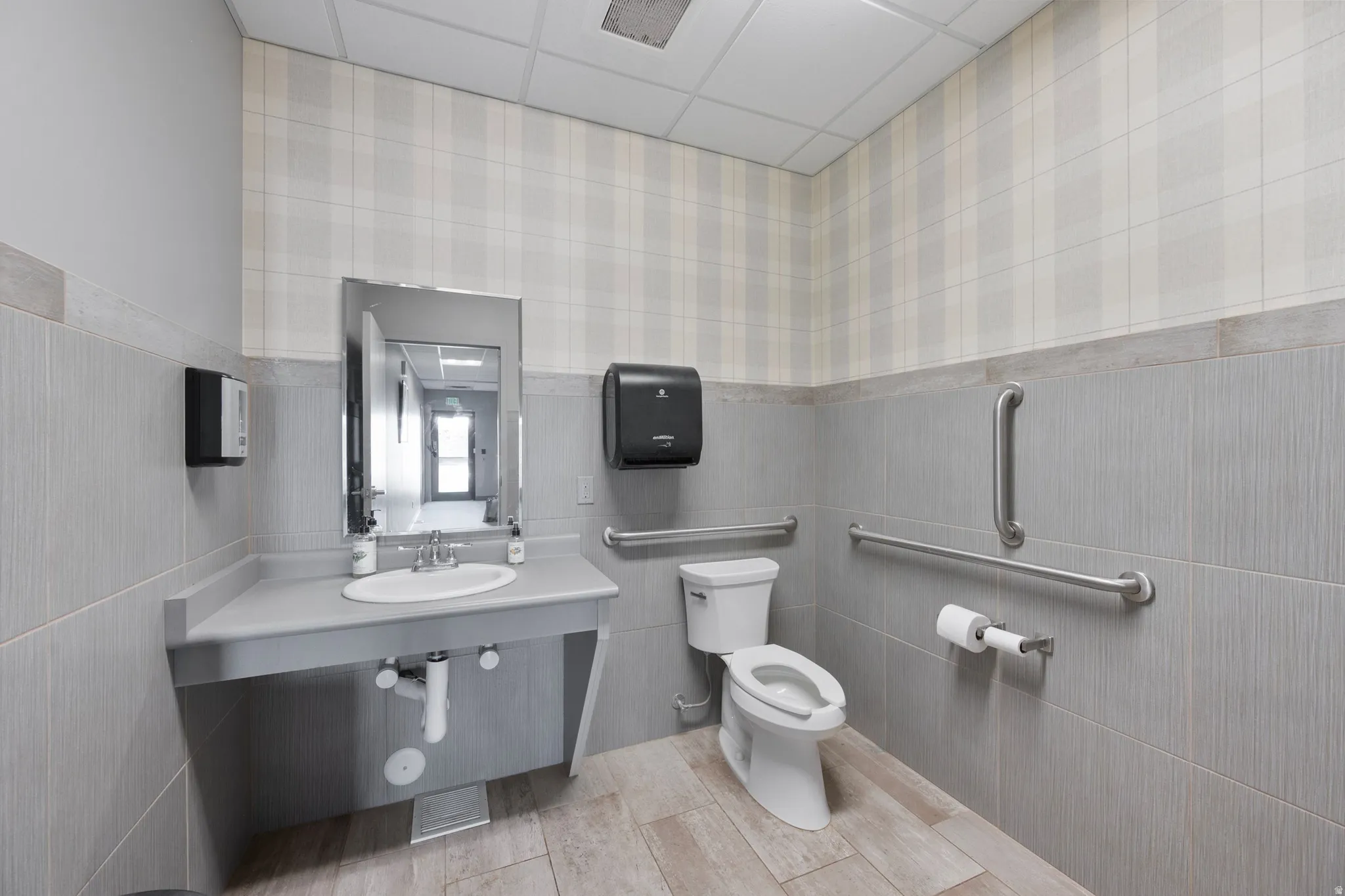 Bathroom featuring vanity, a paneled ceiling, a wainscoted wall, wallpapered walls, and tile walls