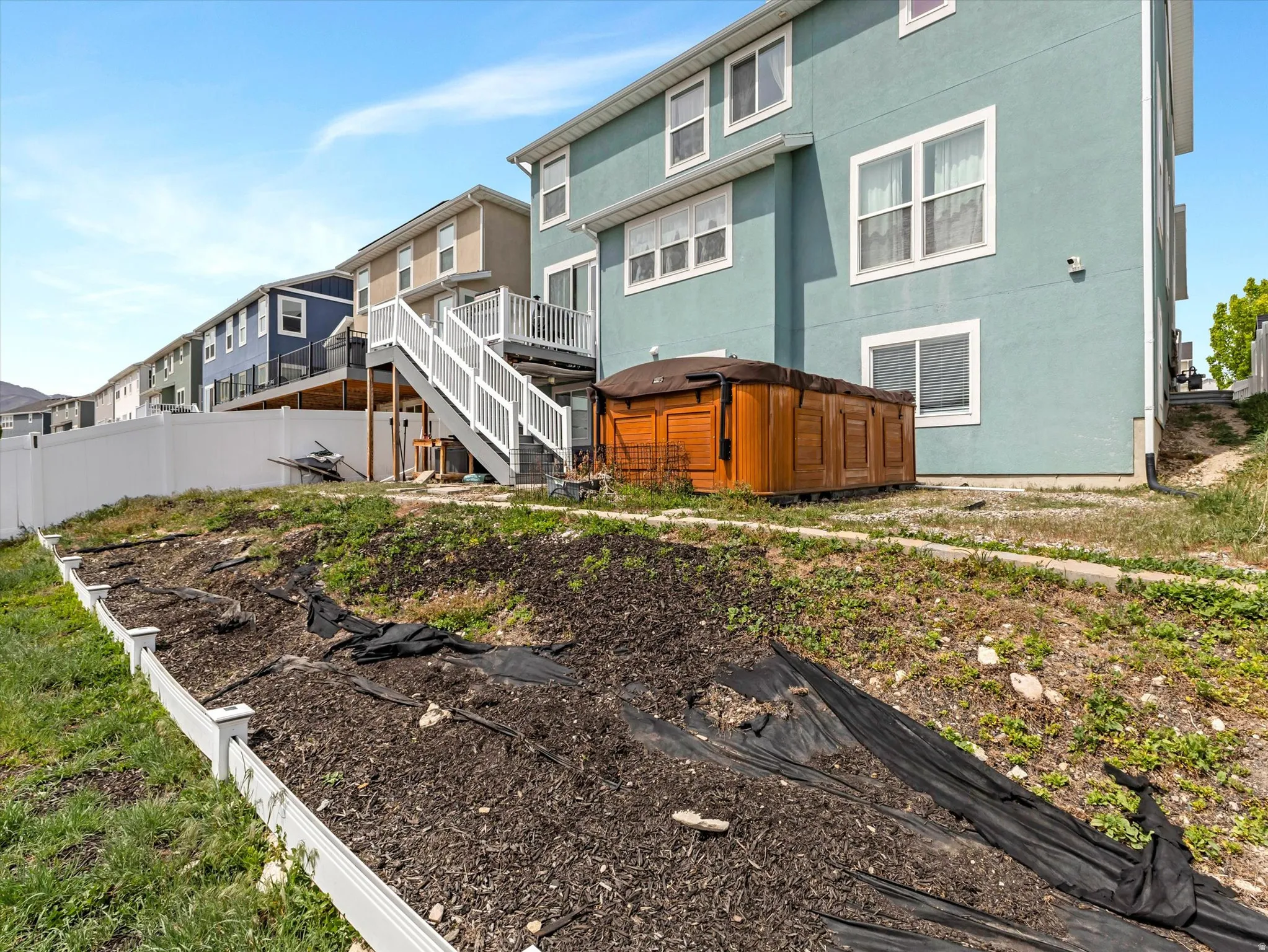 Back of house featuring stucco siding, a wooden deck, and a garden