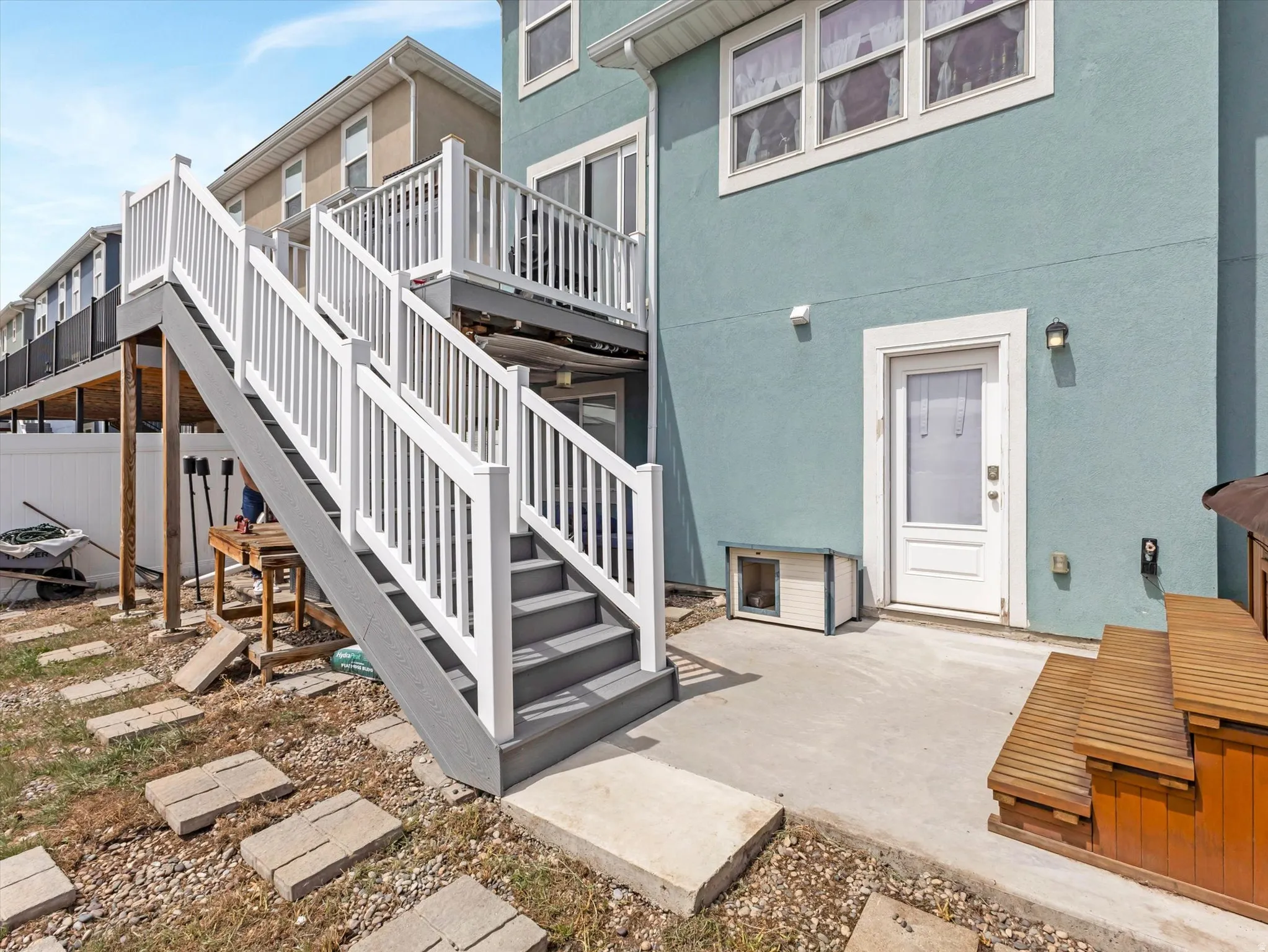View of exterior entry with stucco siding, a deck, and a patio area