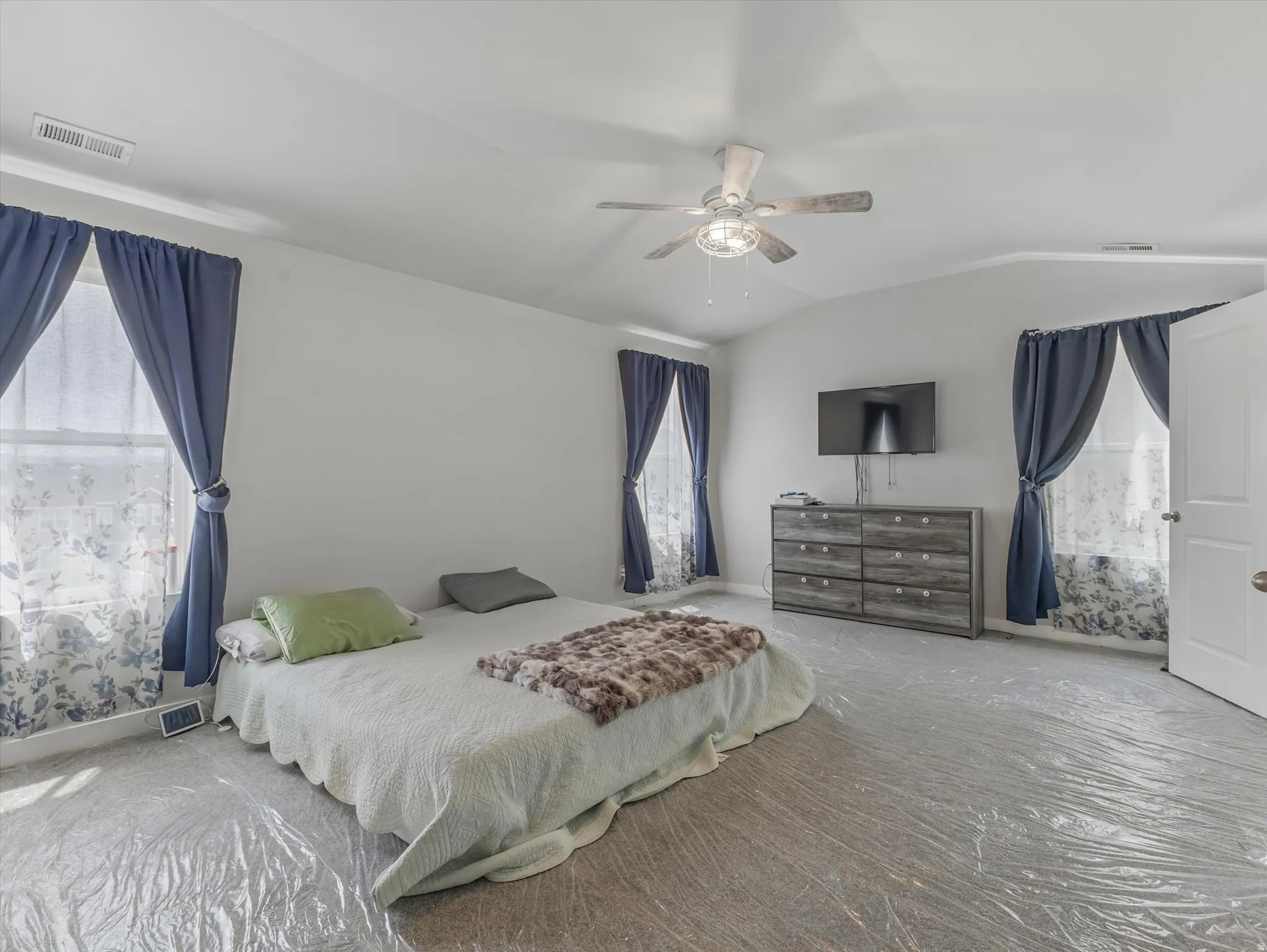 Bedroom featuring multiple windows, vaulted ceiling, and a ceiling fan