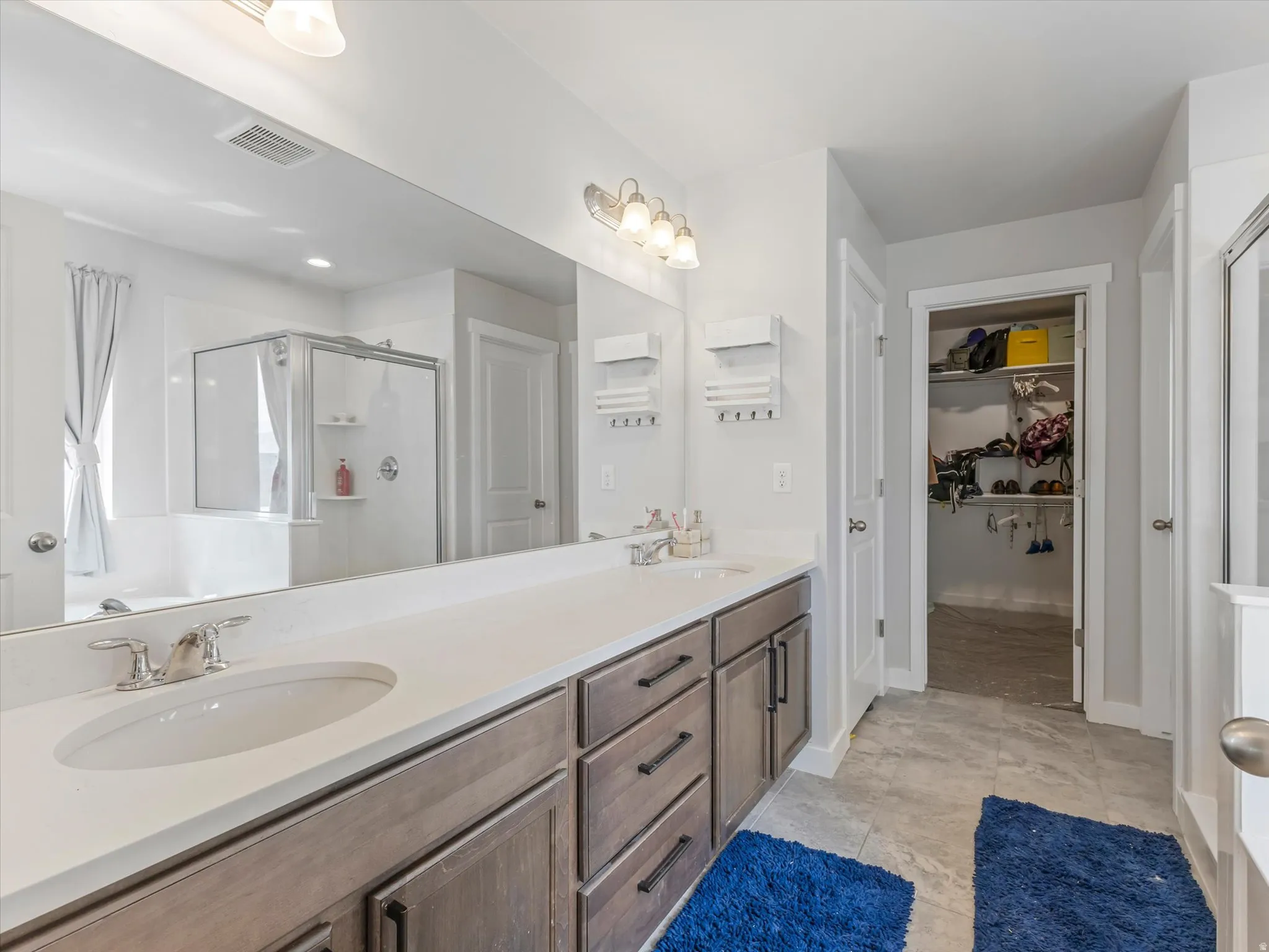 Bathroom with double vanity, a stall shower, and a walk in closet