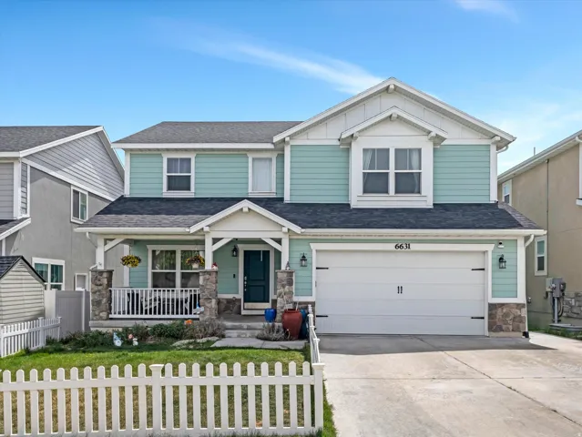 Craftsman house with stone siding, covered porch, driveway, a fenced front yard, and an attached garage