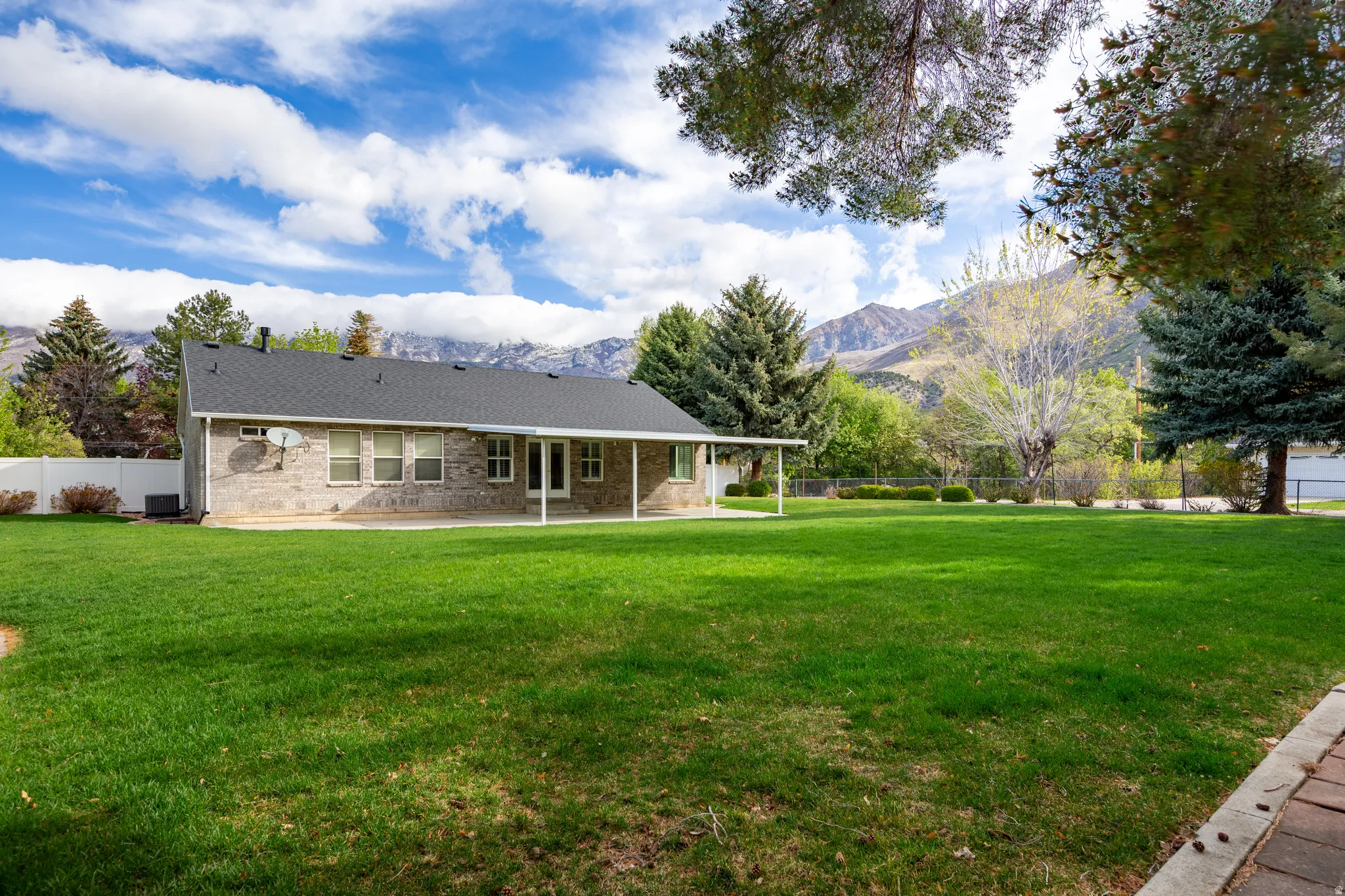Rear view of house with a fenced backyard, a patio area, a mountain view, and brick siding
