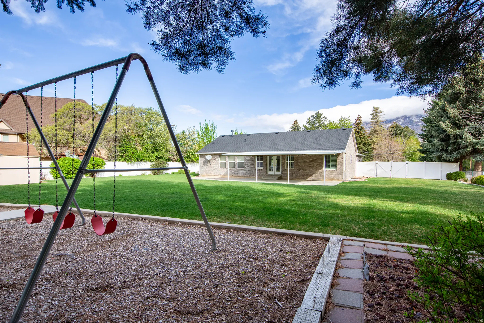 View of playground featuring a fenced backyard, a patio, and a gate