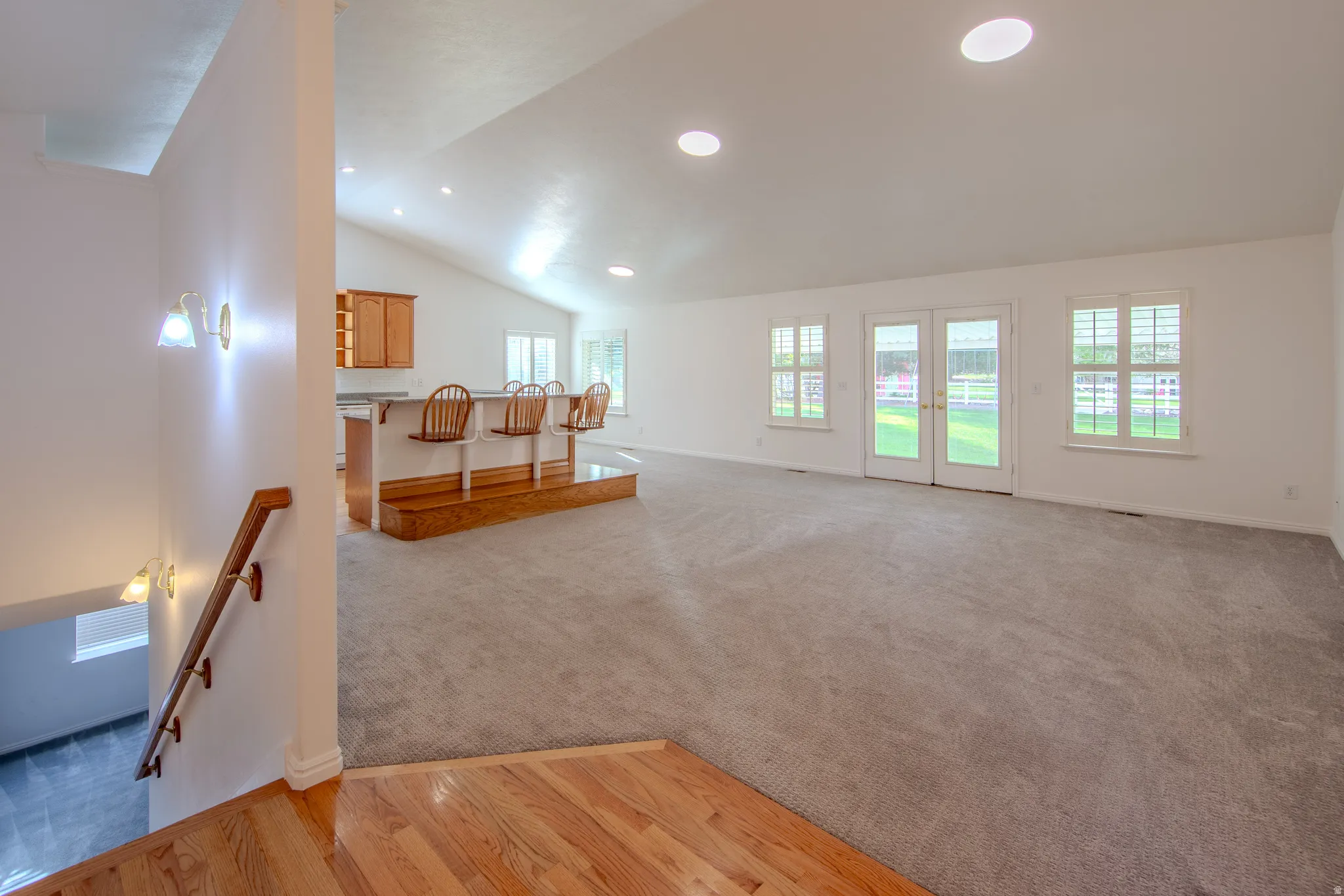 Living room with vaulted ceiling, french doors, light carpet, recessed lighting, and light wood-type flooring