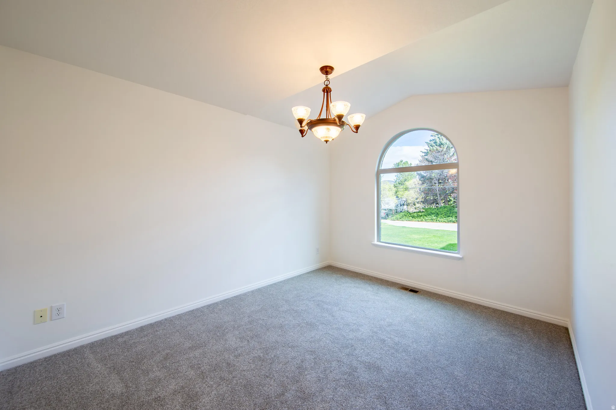 Carpeted spare room with suspended lighting and lofted ceiling