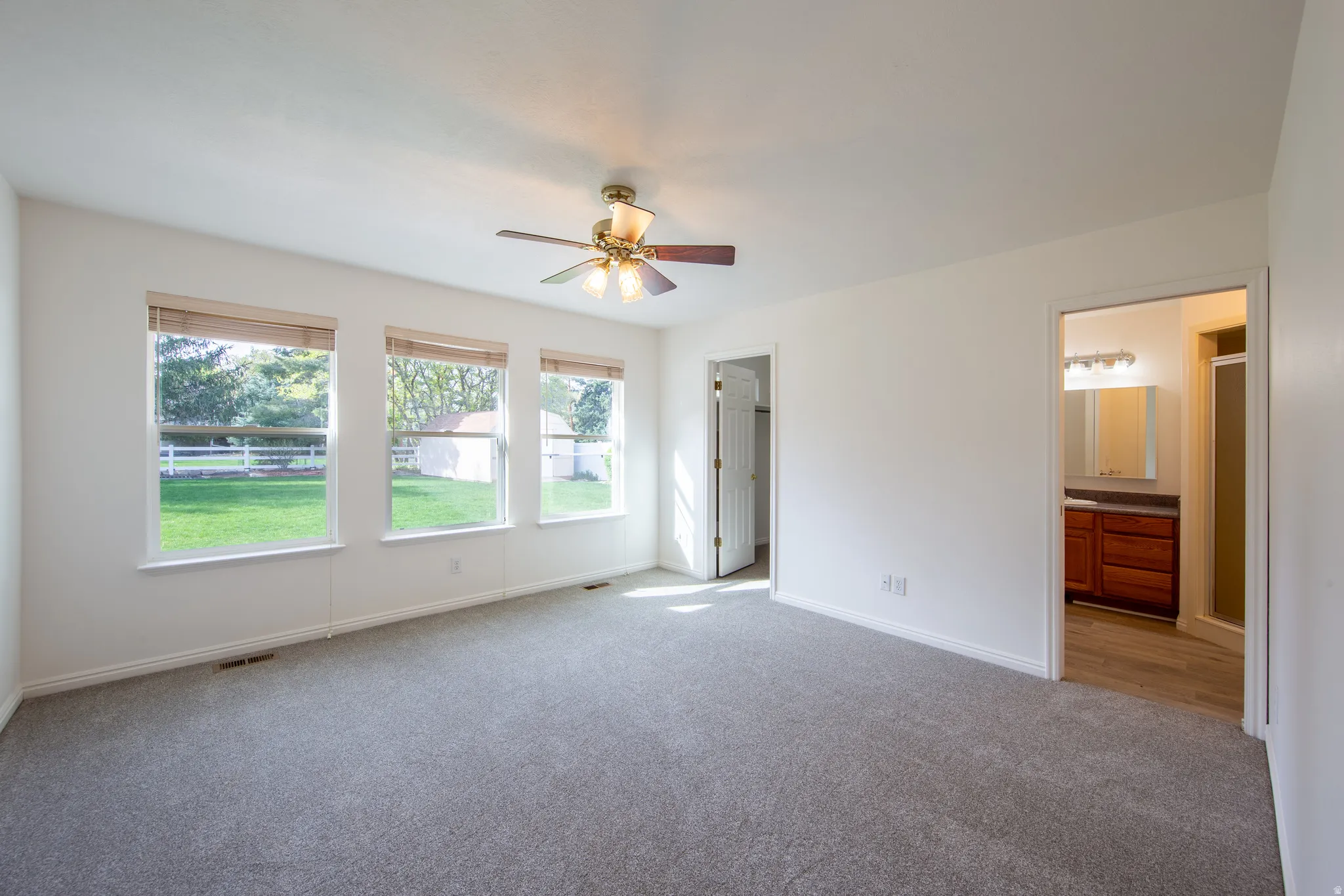 Unfurnished bedroom featuring carpet, ceiling fan, and ensuite bath
