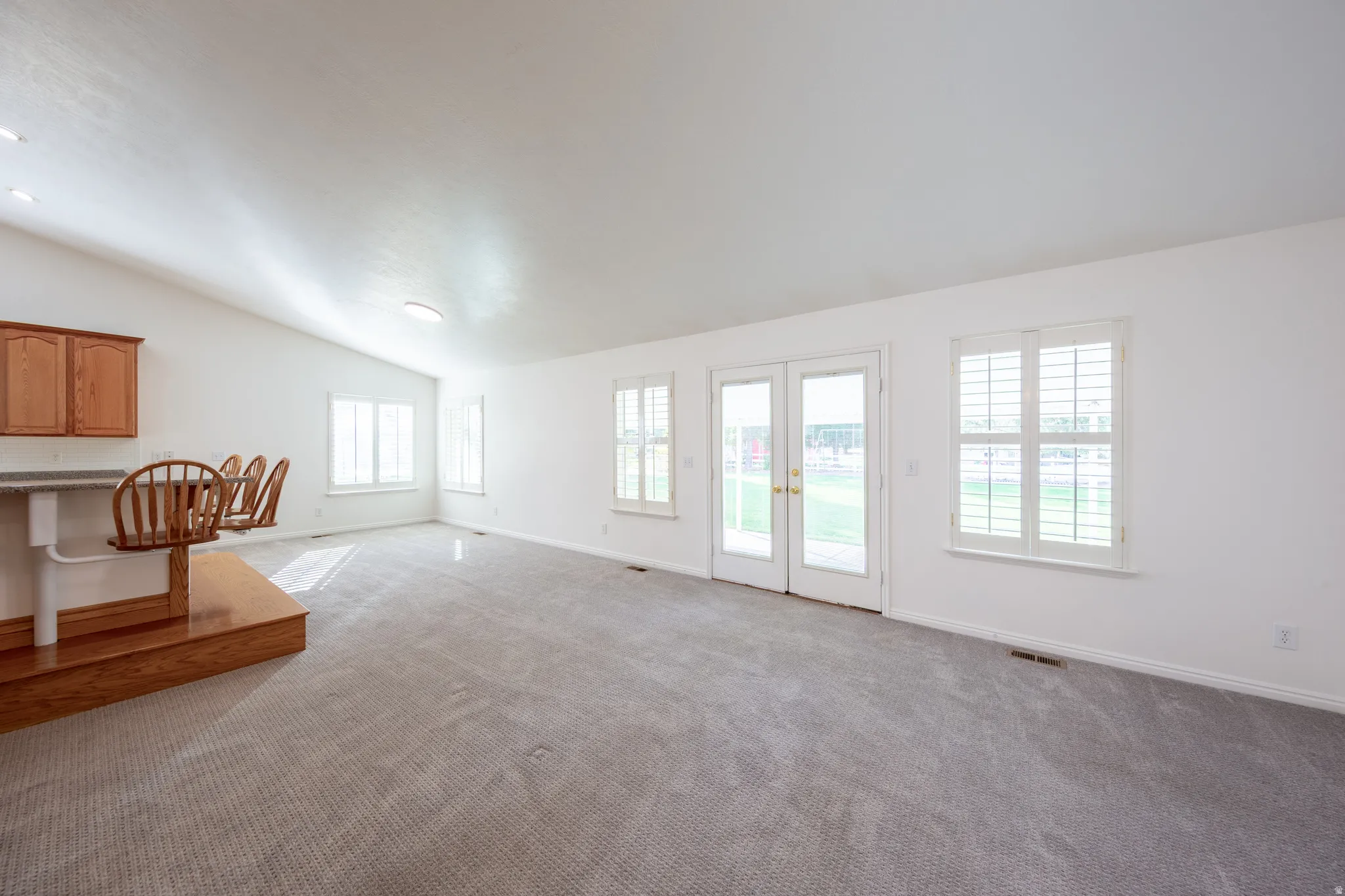 Unfurnished living room with french doors, carpet floors, and lofted ceiling