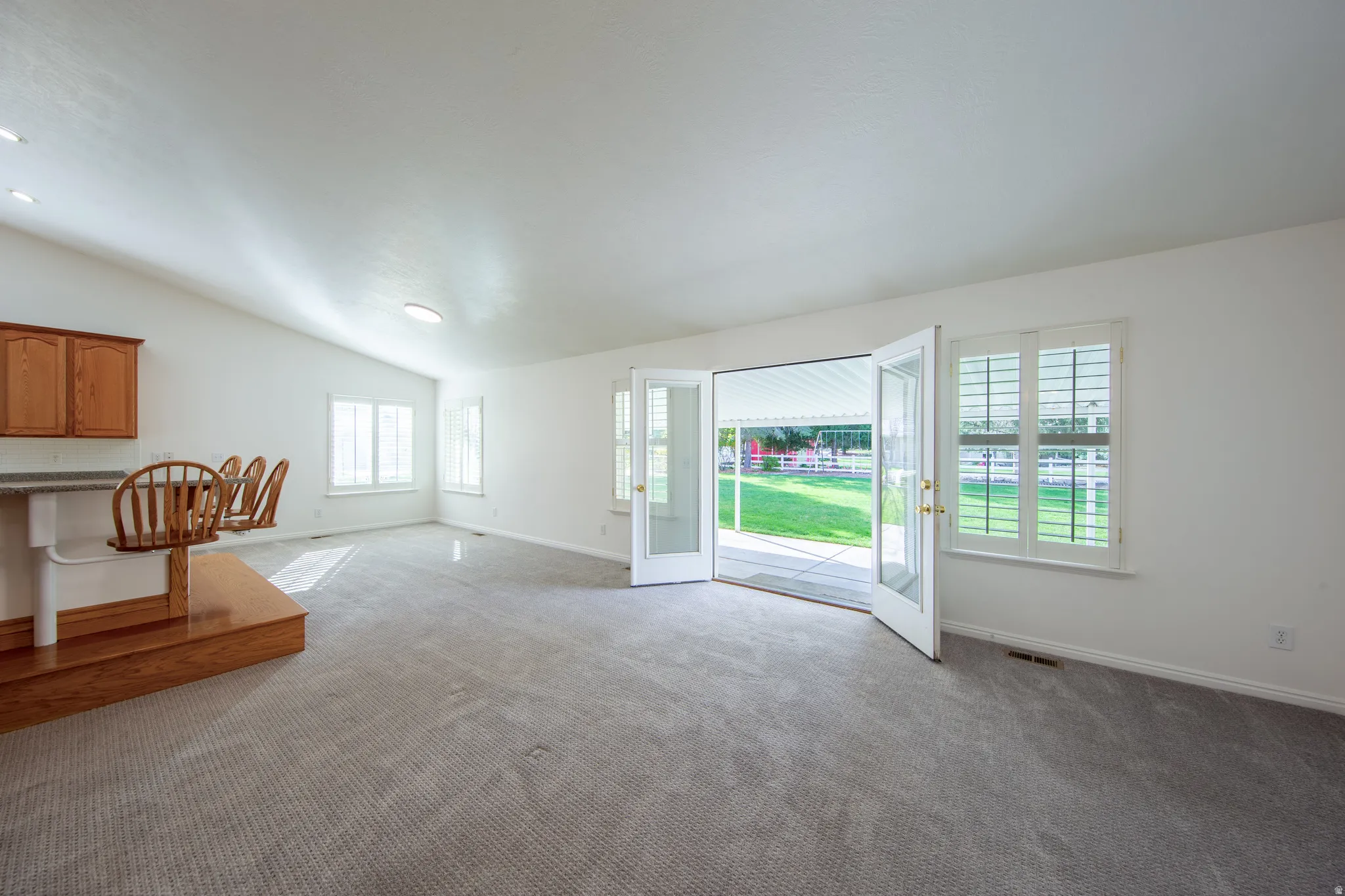 Unfurnished living room with carpet floors and vaulted ceiling