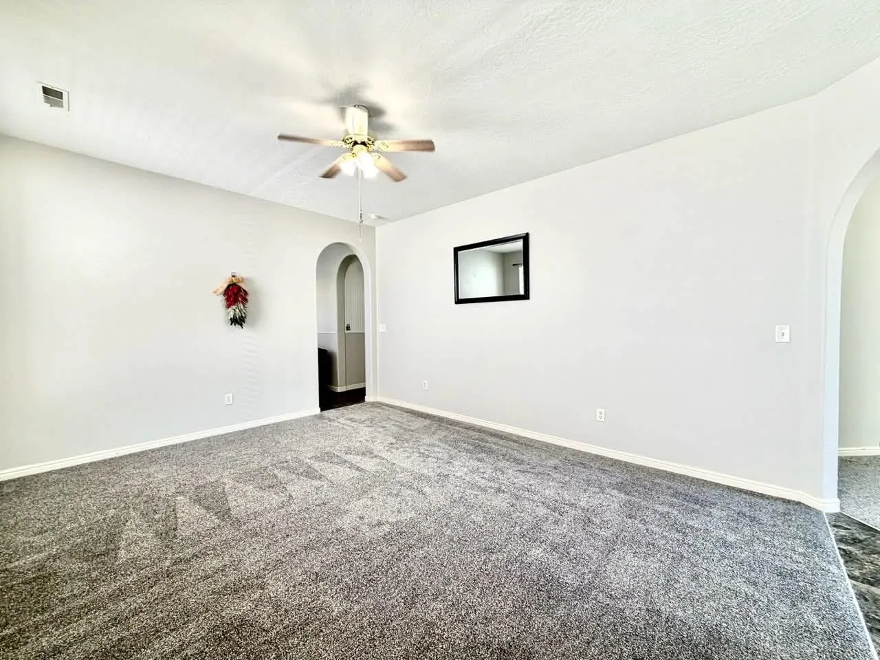 Expansive interior space featuring fresh gray carpeting, neutral wall paint, and white trim