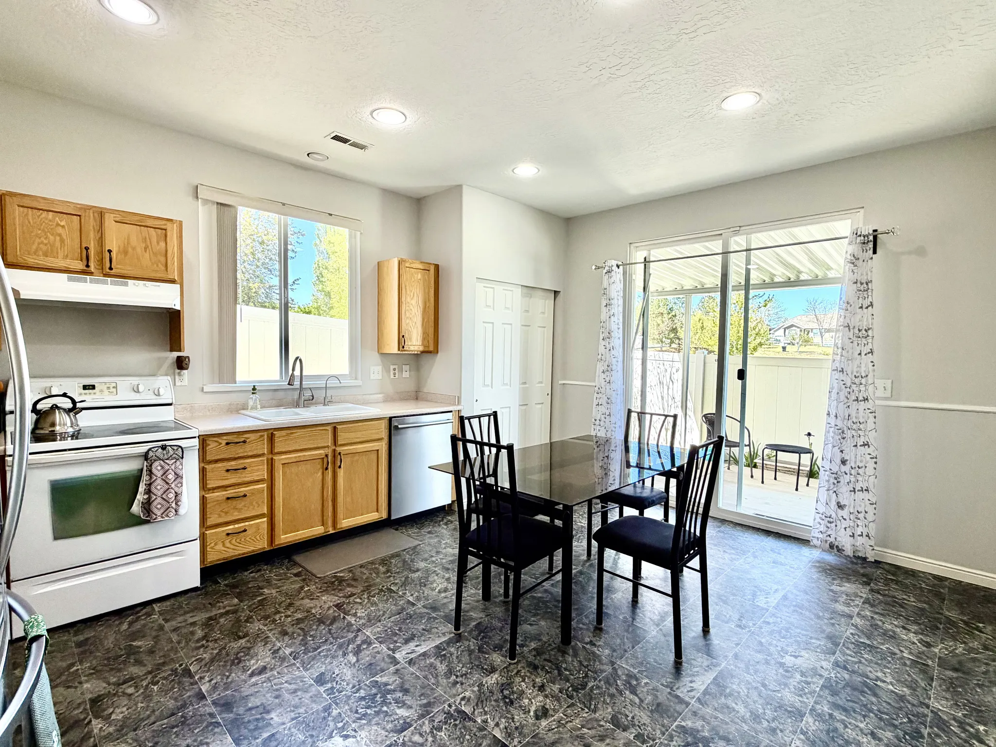 Kitchen and dining area featuring wood-finish cabinetry, a white electric range, and a stainless steel dishwasher