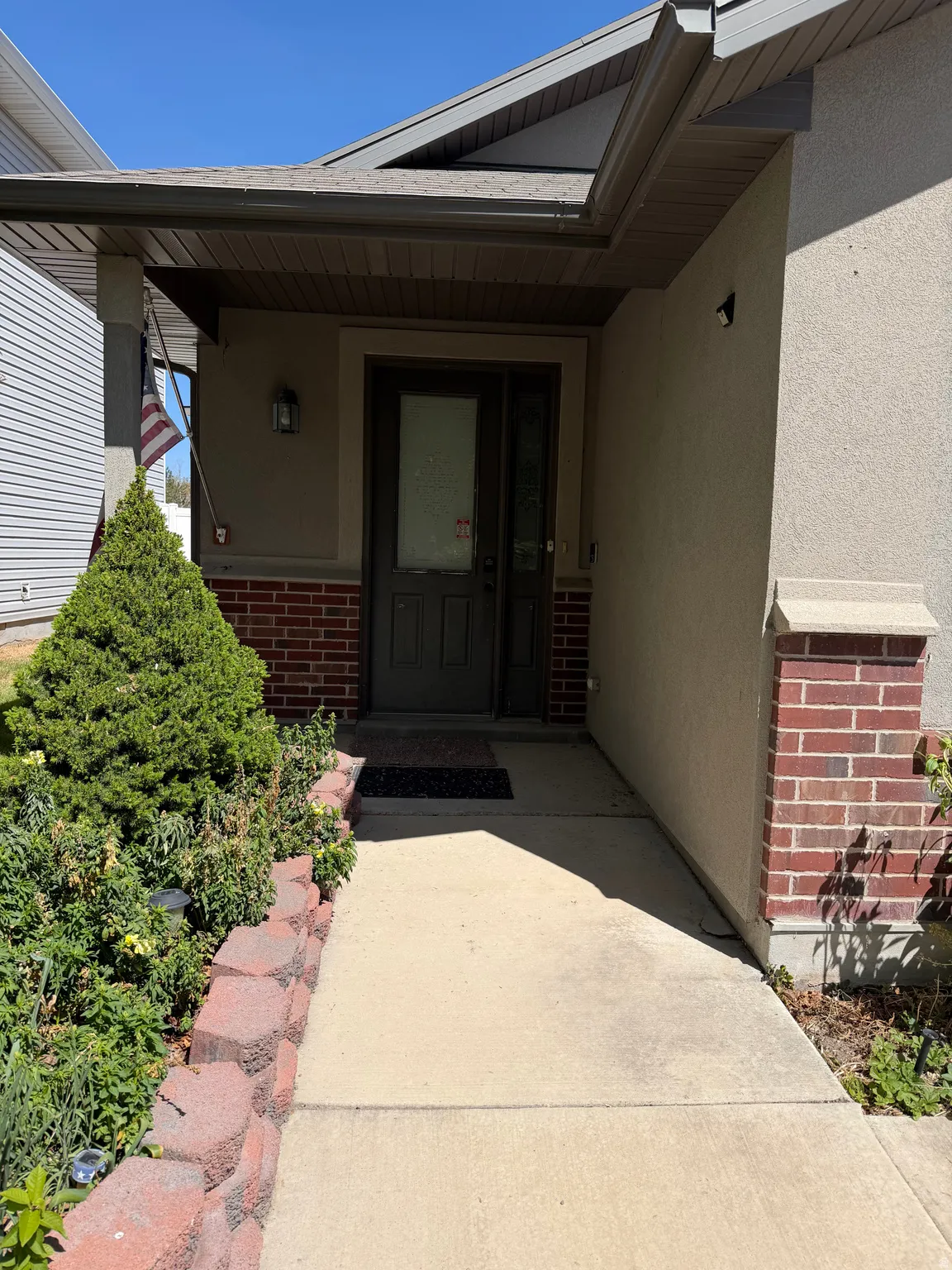 View of exterior entry with brick siding, stucco siding, and a porch