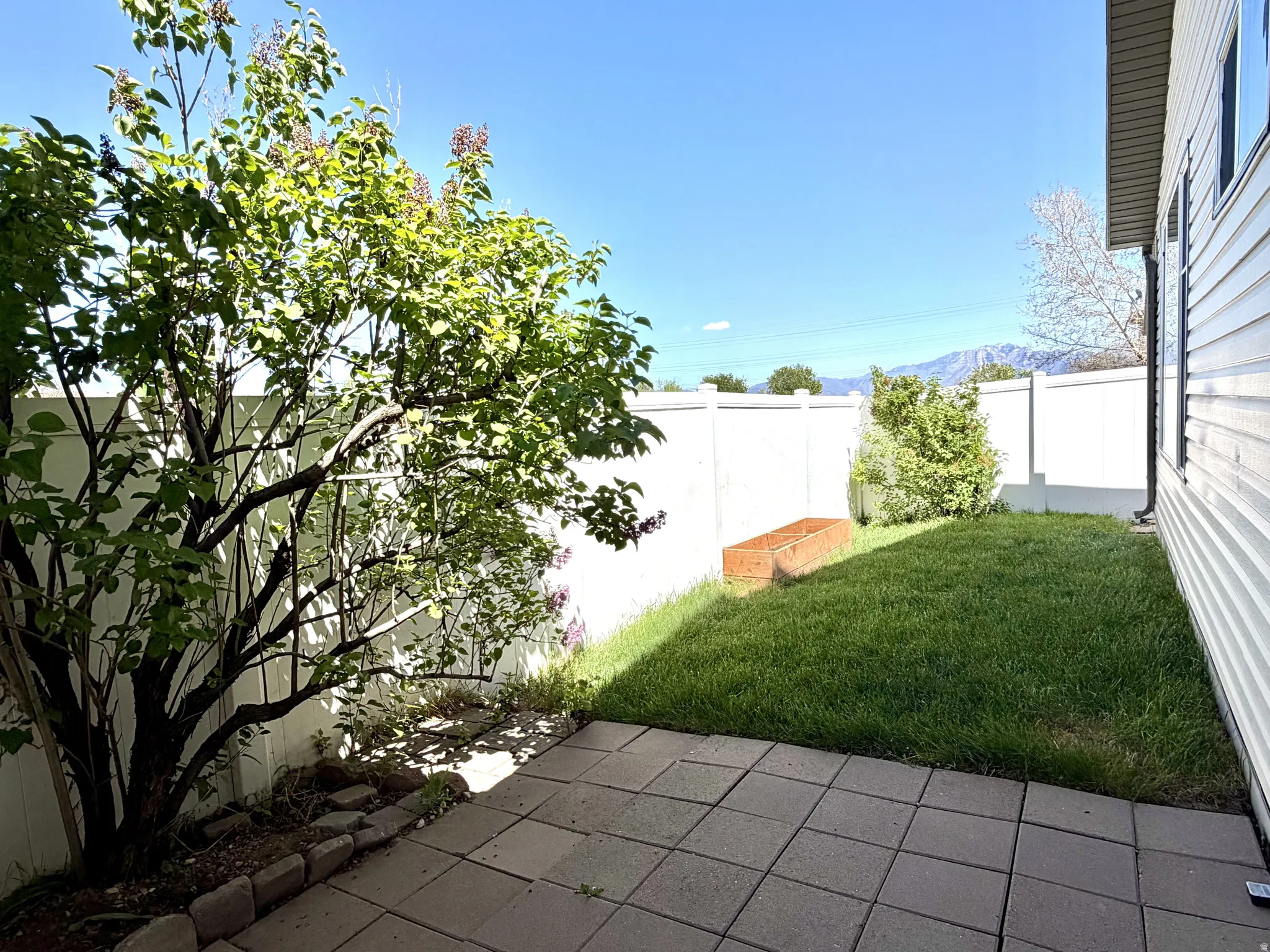 Private patio with paver stones and a lush grassy area