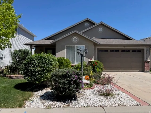 Stucco exterior residence featuring a front-facing garage with horizontal paneling, a covered entry, and a pitched roofline